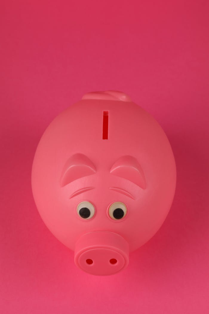 Close-up photo of a pink piggy bank on a vibrant pink background, symbolizing savings and finance.